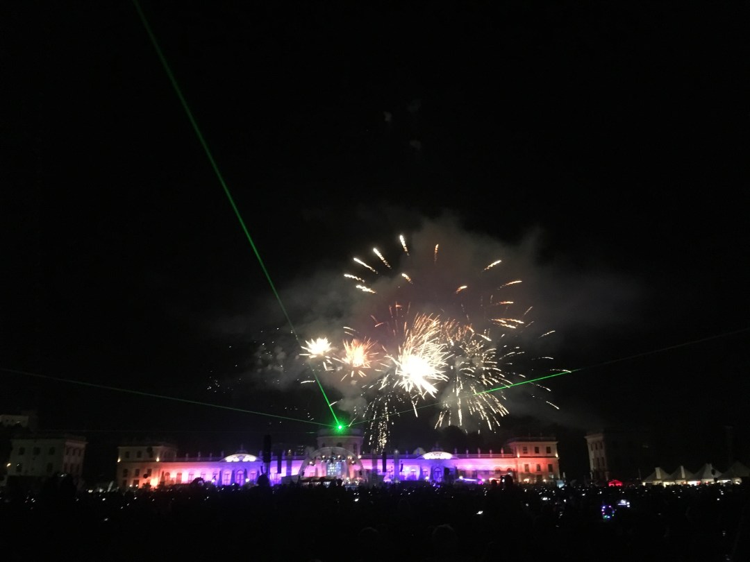 Feuerwerk hinter der lila-orange beleuchteten Orangerie